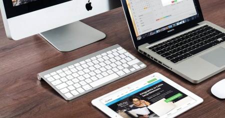 A computer, tablet, and laptop on a desk with multiple apps open.