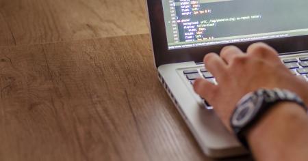 A hand typing on a laptop keyboard.